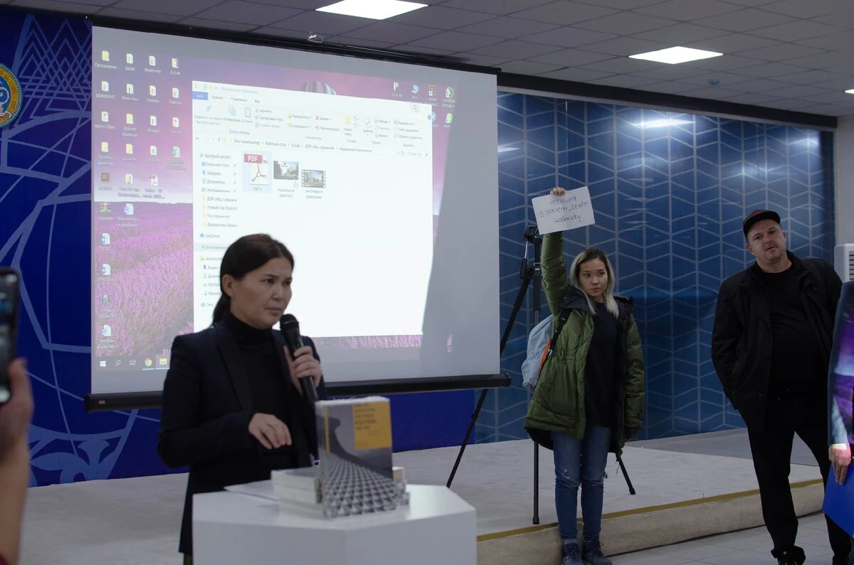 Выступление представителя Urban Forum. На заднем фоне девушка-активист, отвлекает.