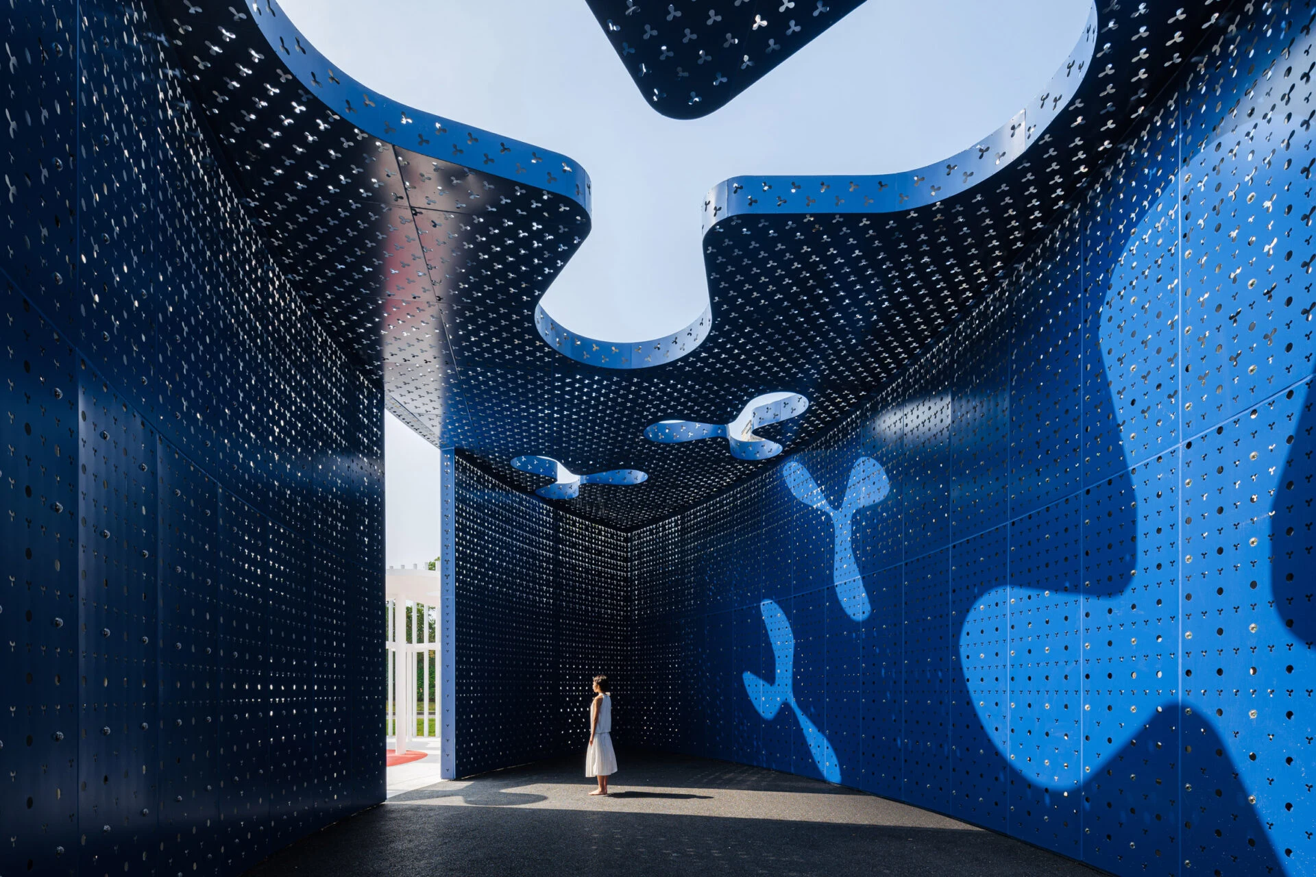 Алюминиевый павильон перфорирован трехлепестковым узором, который повторяется на протяжении всего проекта.