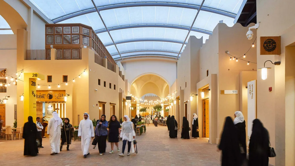 Атмосфера района The Souk под единой защитной кровлей. Архитектура воссоздает геометрию традиционного арабского базара с теплыми песчаными оттенками стен, деревянными элементами и камерными пешеходными улицами. Атмосфера района The Souk под единой защитной кровлей. Архитектура воссоздает геометрию традиционного арабского базара с теплыми песчаными оттенками стен, деревянными элементами и камерными пешеходными улицами.